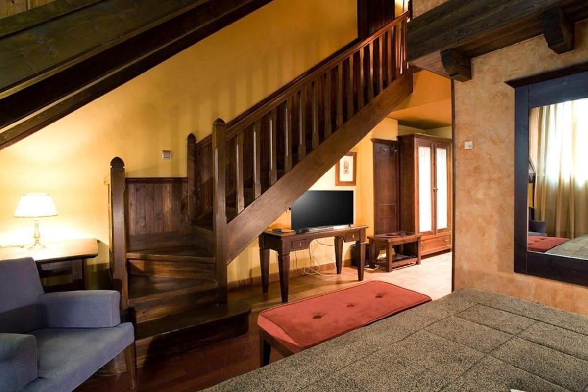 Una sala de estar acogedora con una escalera de madera, un televisor y un sofá.