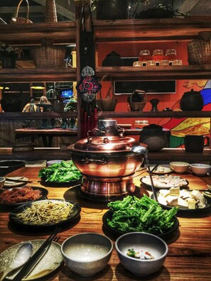A traditional Asian restaurant with a central hot pot, various dishes, and a wooden interior.