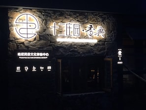 Fachada de edificio con señalización iluminada, incluyendo un logotipo circular grande y caracteres chinos.