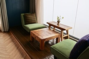Una habitación con un sofá verde, una mesa de centro de madera y una pequeña mesita de noche con una planta.