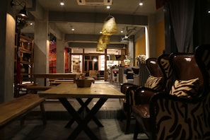 Interior de restaurante con mesas y sillas de madera, cestas colgantes e iluminación colgante.