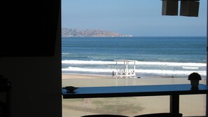 A view of the ocean from a window overlooking a beach with a lifeguard tower. - 4.- HNA Mirador El Faro (La Serena)