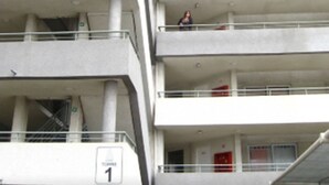 Un edificio de varios pisos con balcones, un ascensor a la vista y un letrero que indica el nombre del edificio.