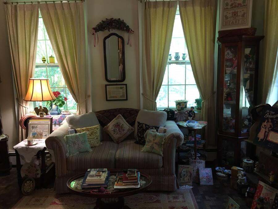 A cozy living room with a striped sofa, a coffee table with books, and a window with curtains.