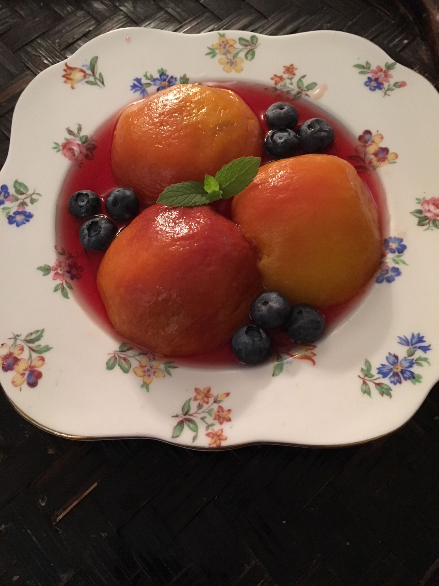 A plate with three round desserts and blueberries on a floral-patterned plate.