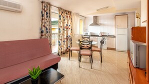A compact living space with a sofa, dining table, chairs, and a kitchenette. - Residencial Marcomar Casa Azahar (Alcala de Xivert)