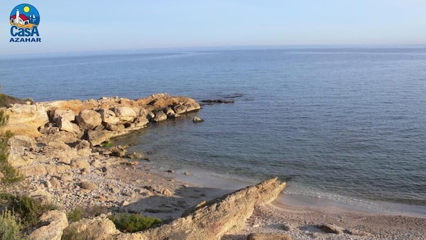 A coastal scene with a wooden walkway leading to a rocky beach. - Residencial Marcomar Casa Azahar (Alcala de Xivert)