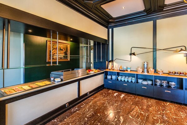 A modern kitchen with a marble floor, a glass display case with food, and a blue cabinet with dishes.