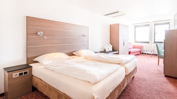Habitación de hotel con dos camas, un escritorio, una silla y un armario.