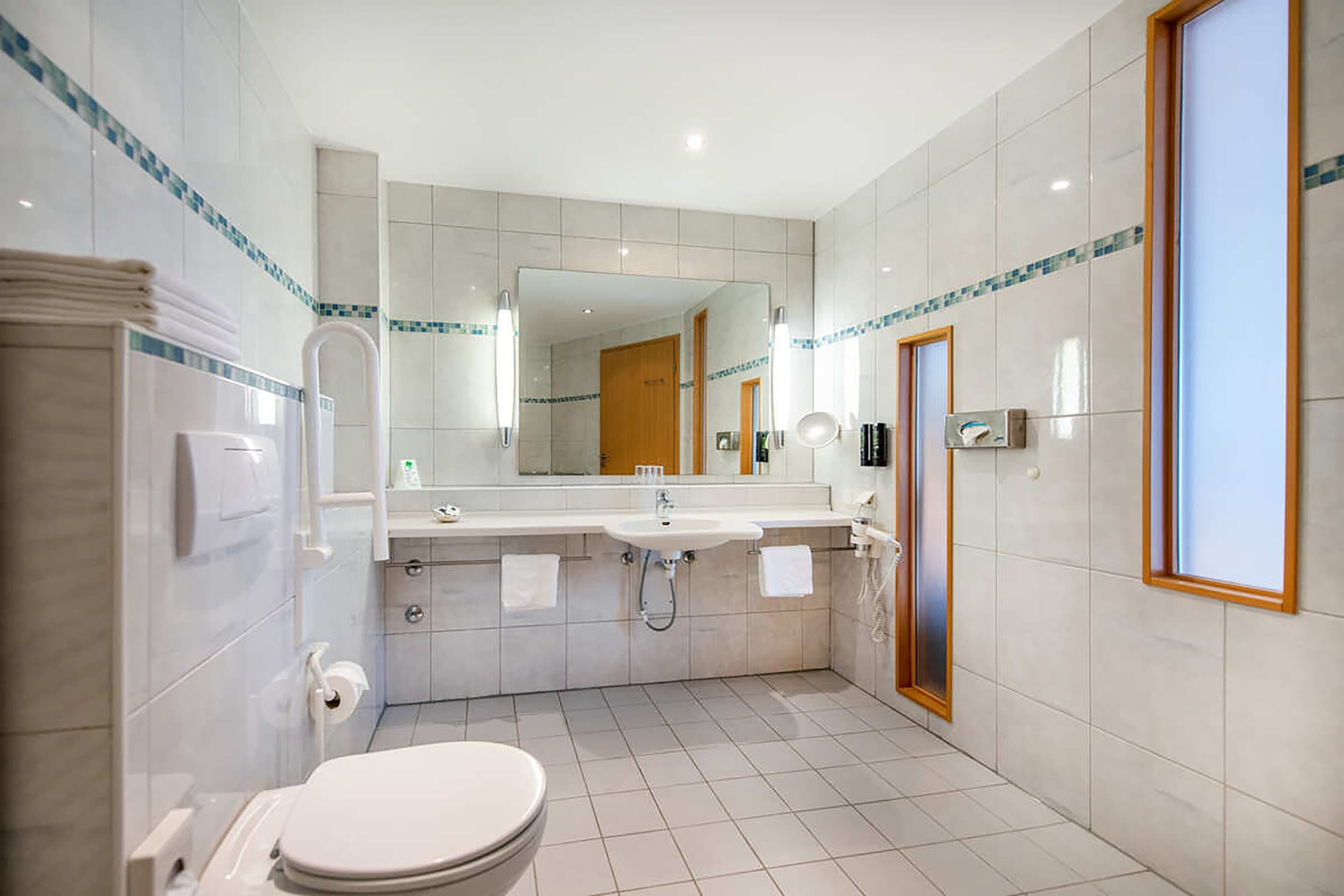 Un baño moderno con inodoro, lavamanos y espejo.