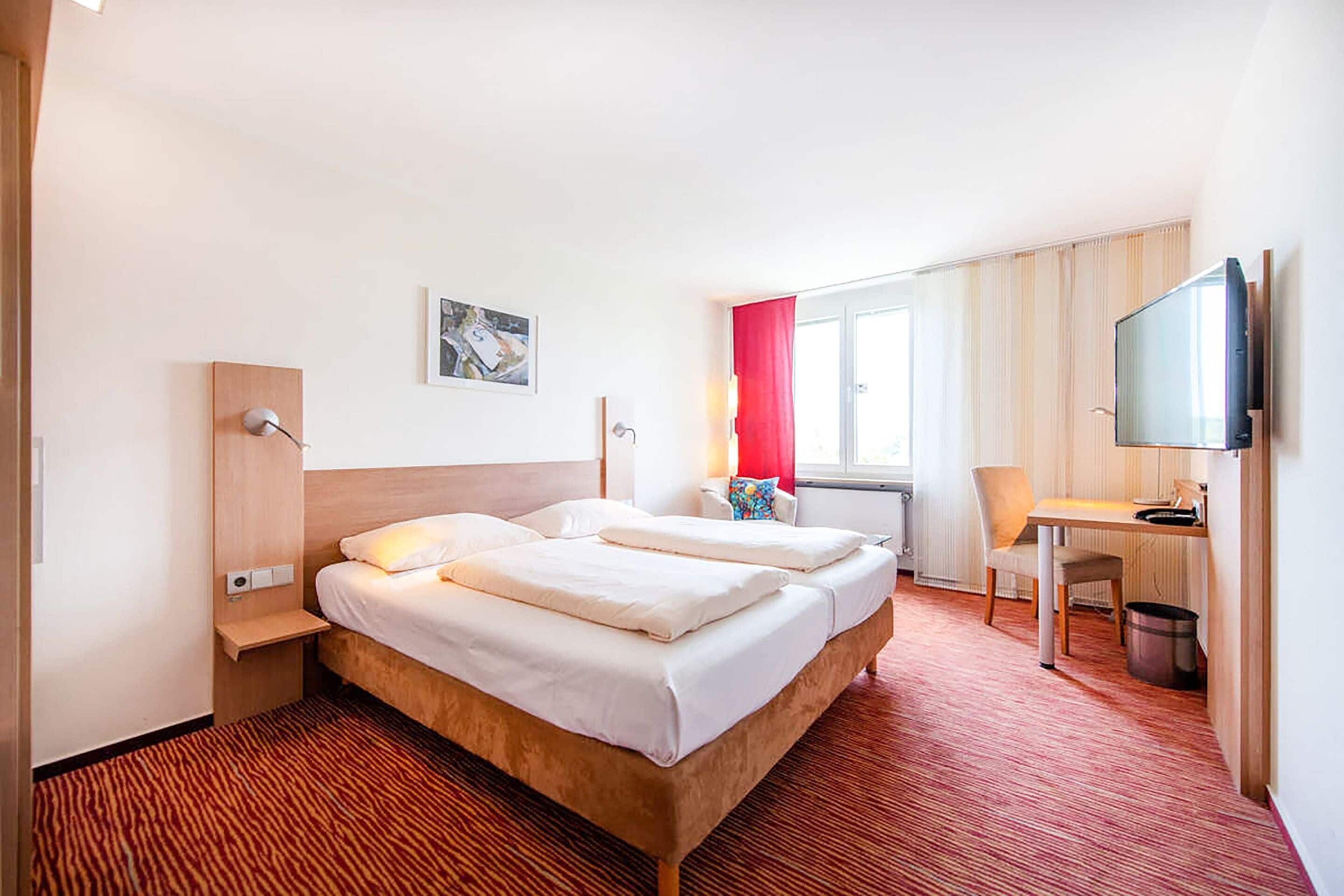 Una habitación de hotel con una cama grande, un escritorio, una silla y un televisor.
