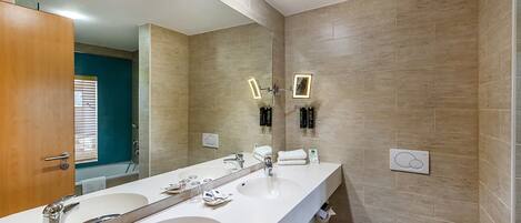 A modern bathroom with two sinks, a large mirror, and a toilet.