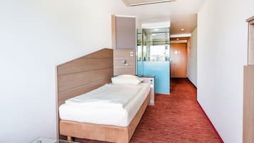 A modern hotel room with a wooden headboard bed, a glass table, and a red carpeted floor.