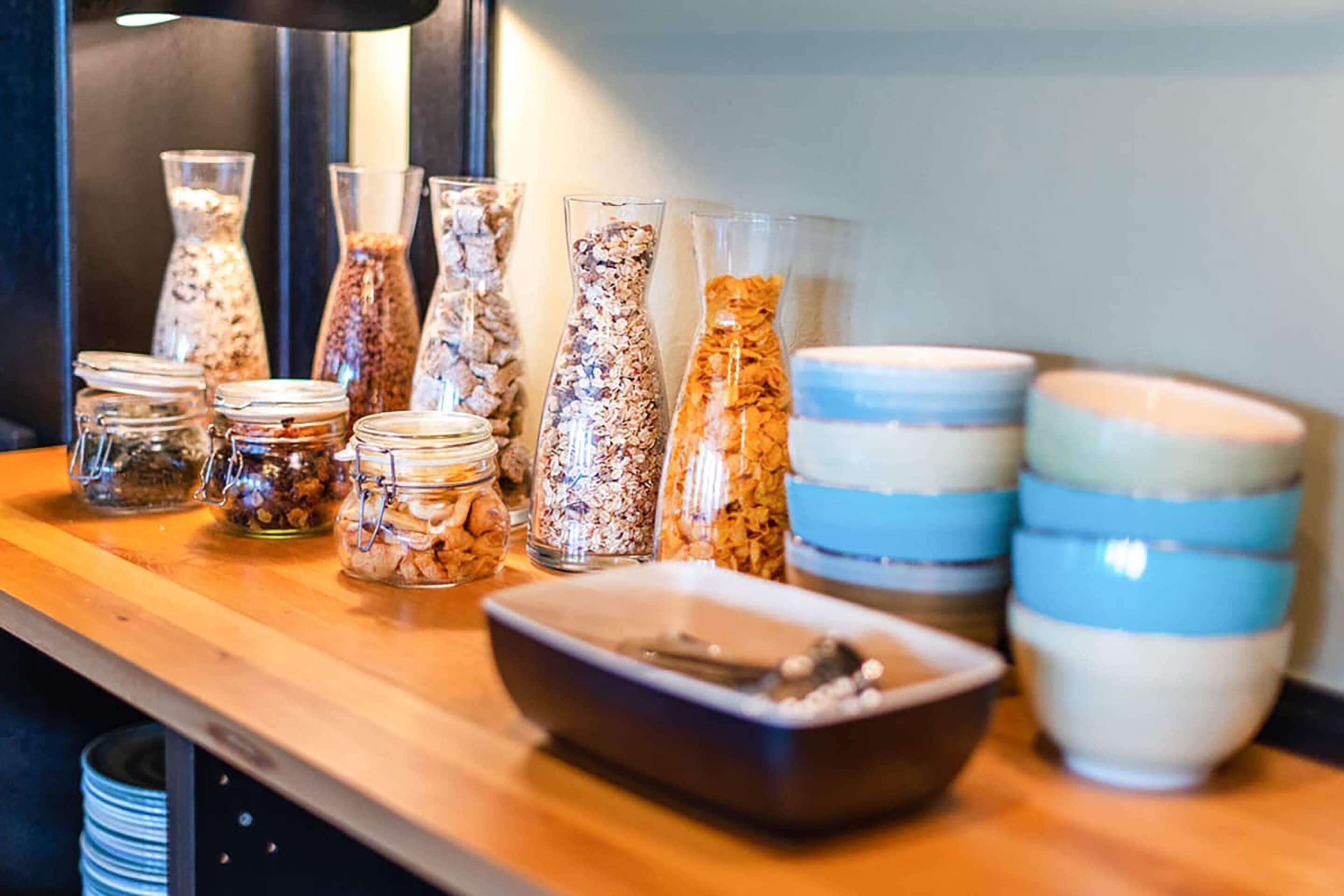 A variety of glass containers and bowls on a wooden table, likely for serving food or drinks.
