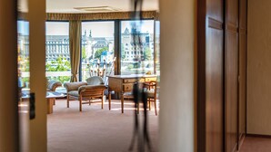 Habitación de hotel con un ventanal grande que ofrece vistas a la ciudad, un escritorio y dos sillas.