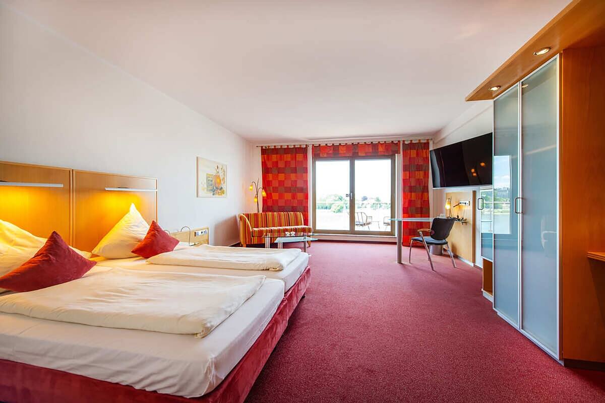 Habitación de hotel con dos camas, televisión, escritorio y silla.