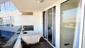 A balcony with a table and chairs, a sliding glass door, and a view of the surrounding buildings. - 5.- HNA Mirador El Faro (La Serena)