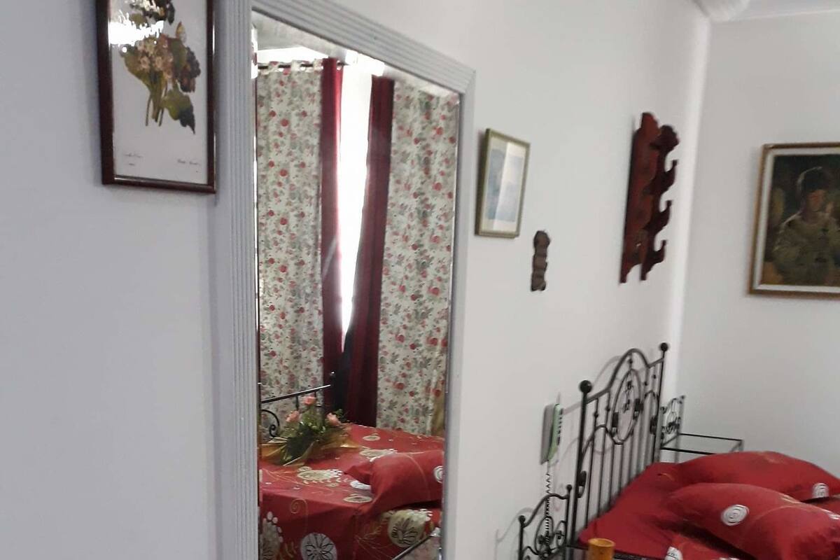 A room with a bed, a chair, a table, and a mirror.