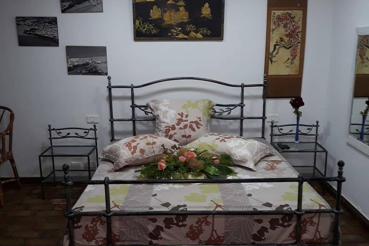 A bedroom with a metal bed frame, floral bedding, and a wall-mounted light fixture.