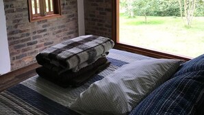 Un dormitorio con un ventanal grande, techo de madera y pared de ladrillo.