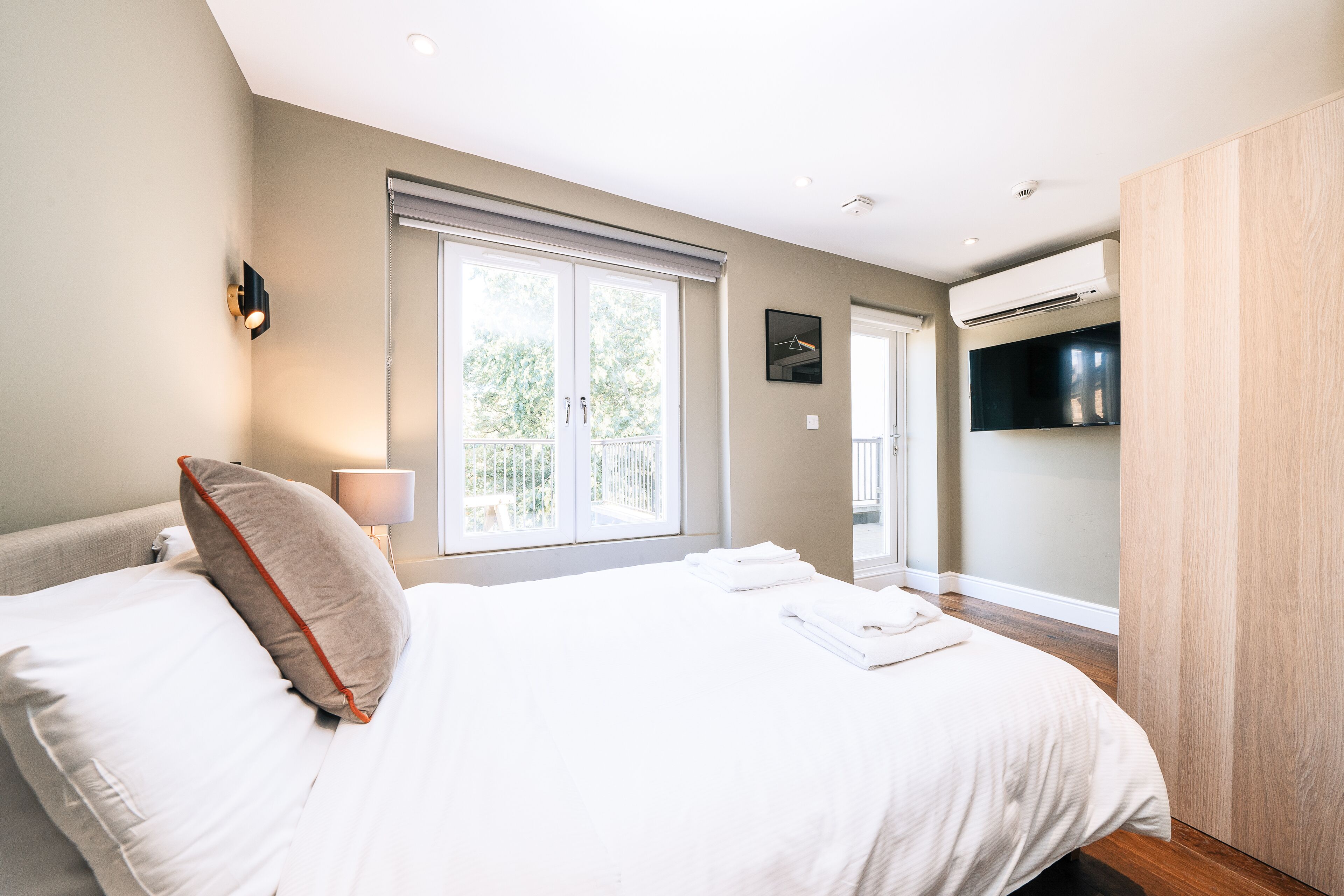Una habitación de hotel moderna con una cama grande, un televisor de pantalla plana y una ventana con vistas a zonas verdes.