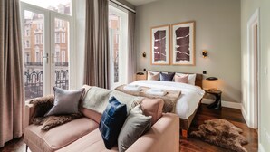 A hotel room with a large bed, a sofa, a window with curtains, and two framed artworks on the wall. - The Knaresborough by Nestor (London)