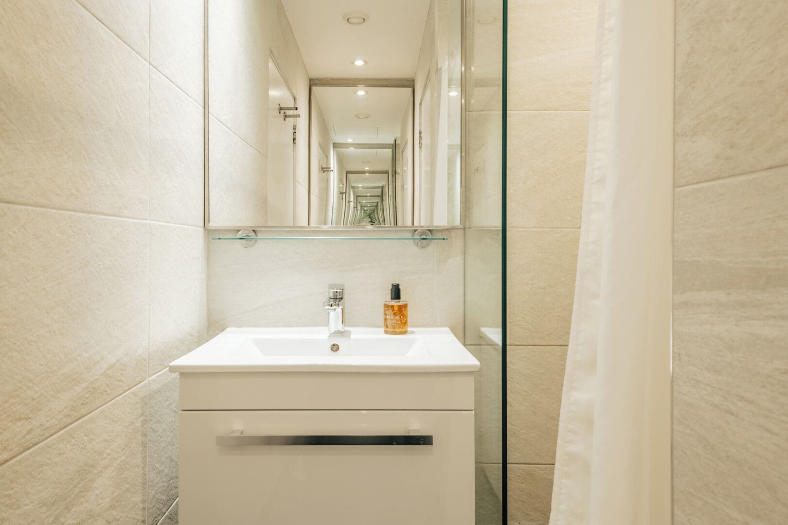 A modern bathroom with a white sink, a mirror, and a glass shower enclosure.