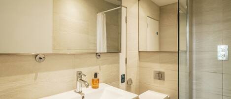 A modern bathroom with a sink, toilet, and glass shower enclosure.