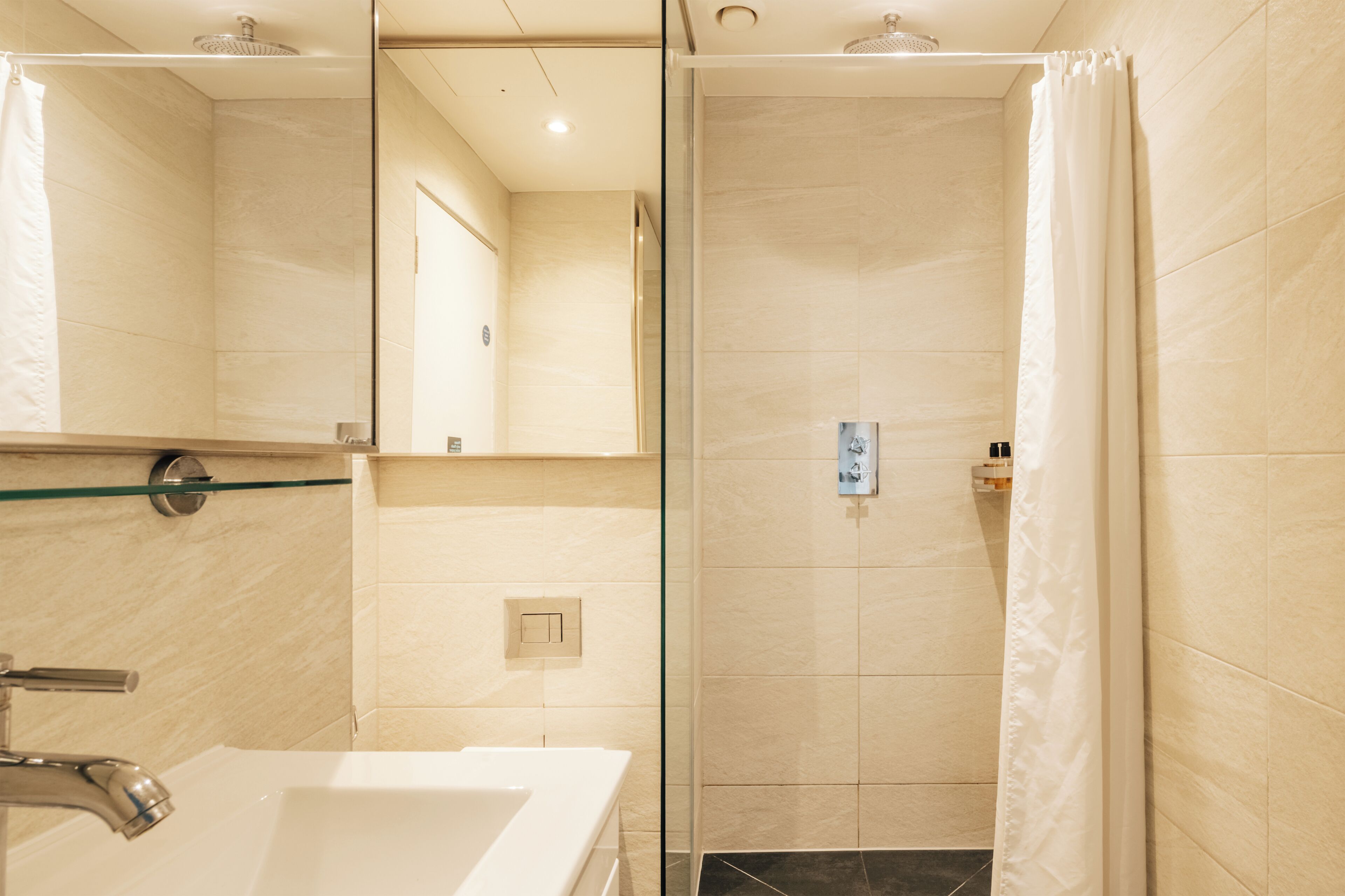 Une salle de bain avec une douche, un lavabo et un miroir.