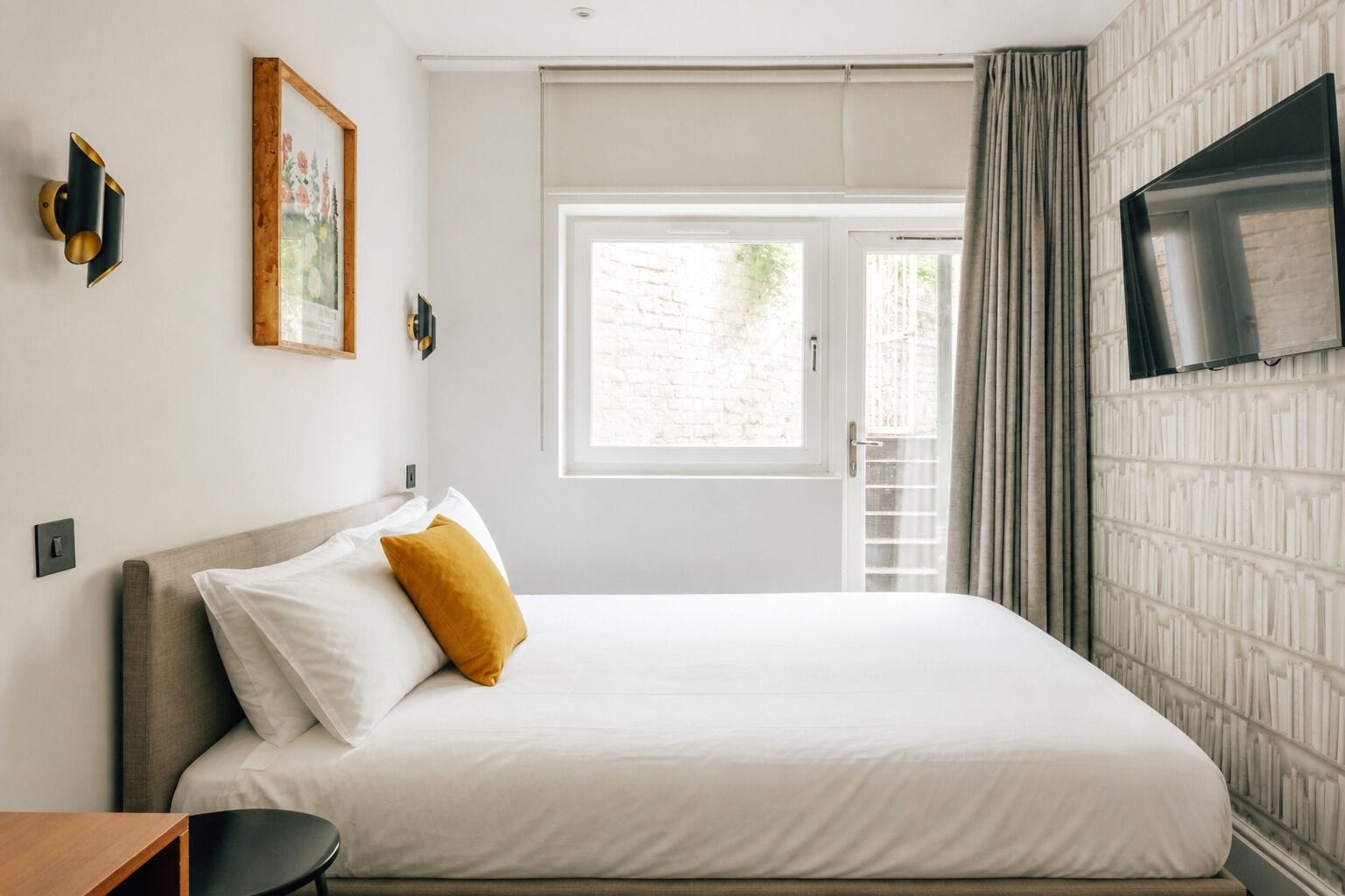 Een slaapkamer met een bed, een televisie, een raam en een deur.