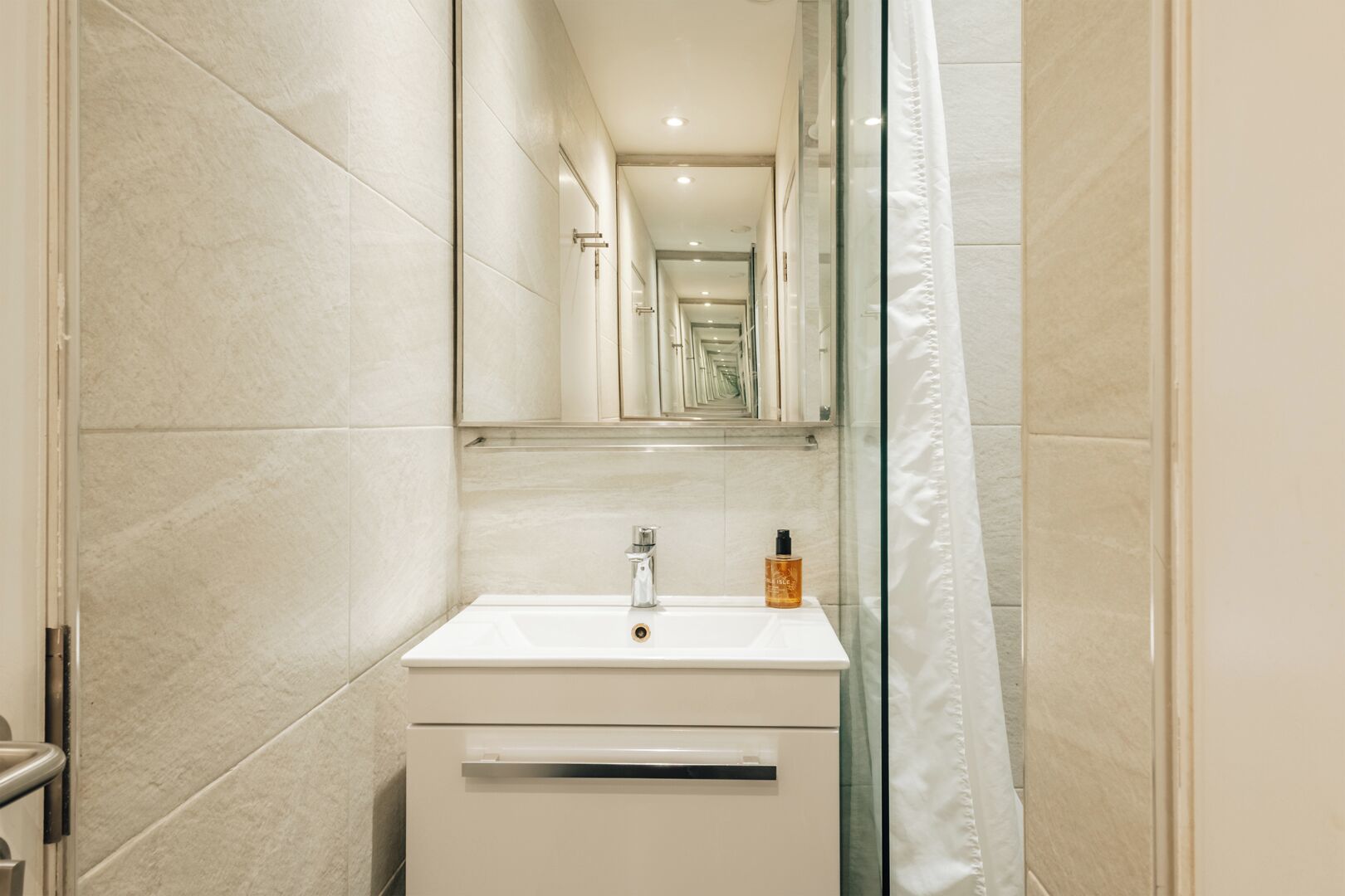 A bathroom with a white sink, a mirror, and a shower curtain.