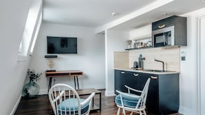 A modern kitchen with a built-in microwave, a dining area with two chairs, and a TV mounted on the wall. - The Knaresborough by Nestor (London)