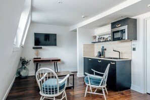 Una cocina moderna con microondas integrado, un comedor con dos sillas y un televisor montado en la pared.
