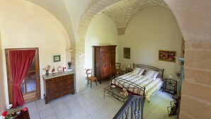 A bedroom with a bed, wooden wardrobe, desk, and chairs. - Mas du Crès (Galargues)