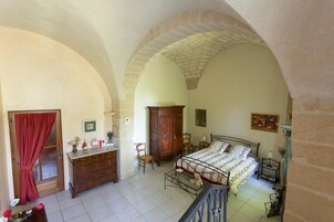 Un dormitorio con cama, armario de madera, escritorio y sillas.