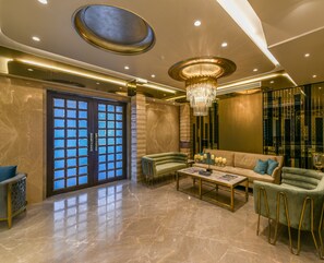 Um hall espaçoso com piso de mármore, um lustre grande e um conjunto de sofás moderno.