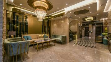 A modern lobby with a chandelier, sofas, a coffee table, and a patterned floor.
