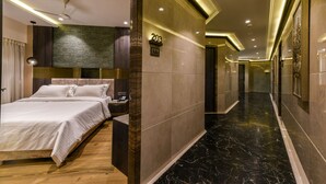 A hotel room with a large bed, a nightstand, a wall-mounted phone, and a number sign indicating room 203. - Hotel Orient Regency (Mumbai)