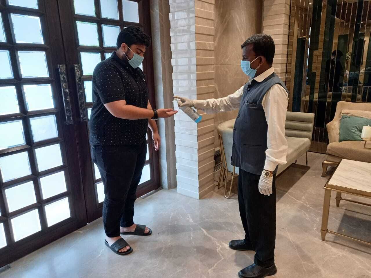 A man handing a card to another man in a modern interior with a sofa and a table.