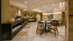 A modern kitchen with a central island, bar area, and seating for dining. - Hotel Orient Regency (Mumbai)