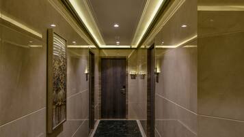 A hallway with marble flooring, wall-mounted artwork, and illuminated ceiling lights.