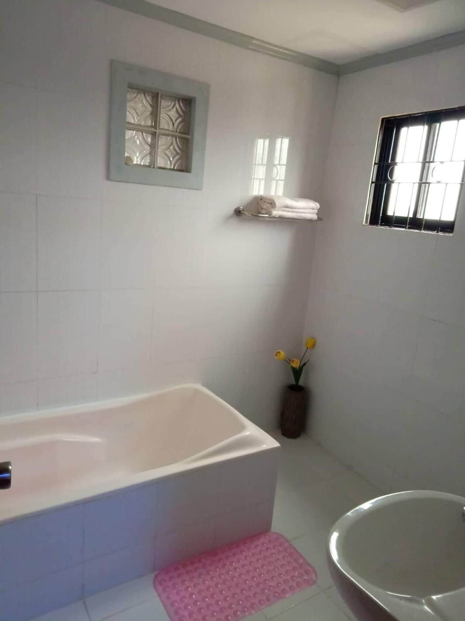A bathroom with a bathtub, a shower, a small window, and a towel rack.