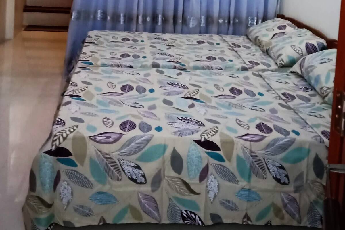 A bedroom with a bed, curtains, a staircase, and a ceiling light.