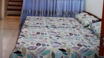 A bedroom with a bed, curtains, a staircase, and a ceiling light.