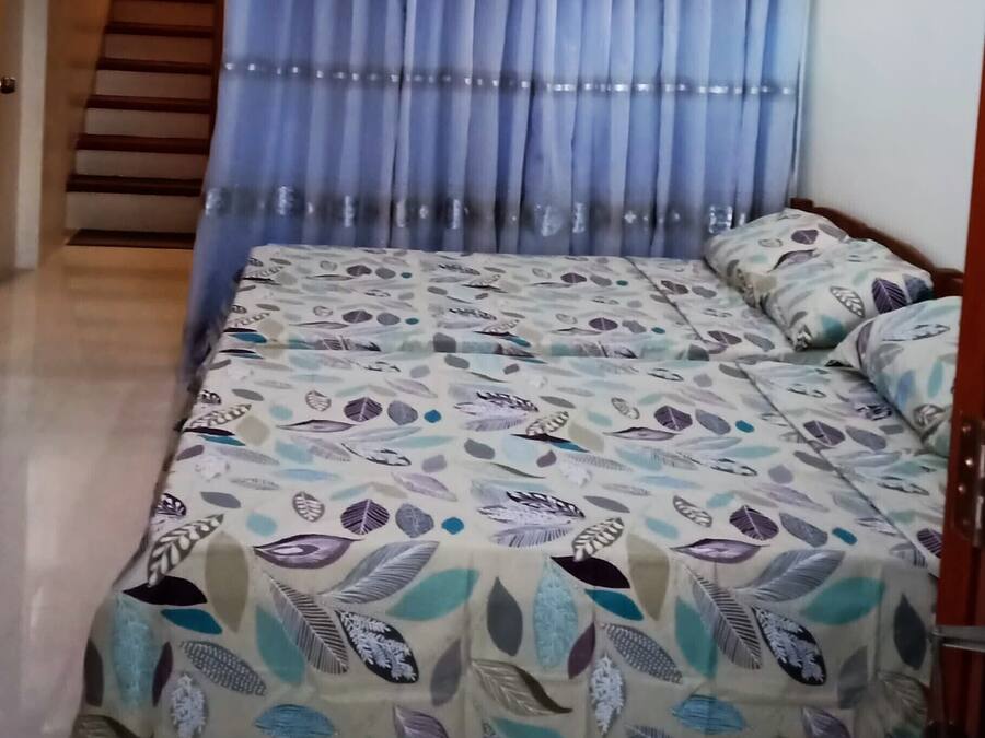 A bedroom with a bed, curtains, a staircase, and a ceiling light.