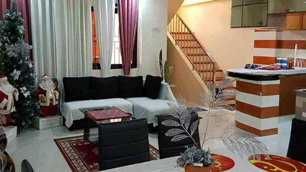 Una sala de estar con un sofá, una mesa de comedor y una escalera que lleva a la cocina.