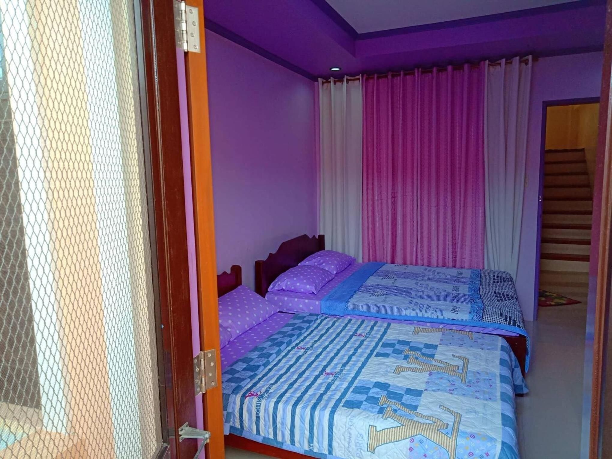 Un dormitorio con dos camas, una puerta de madera y una escalera.