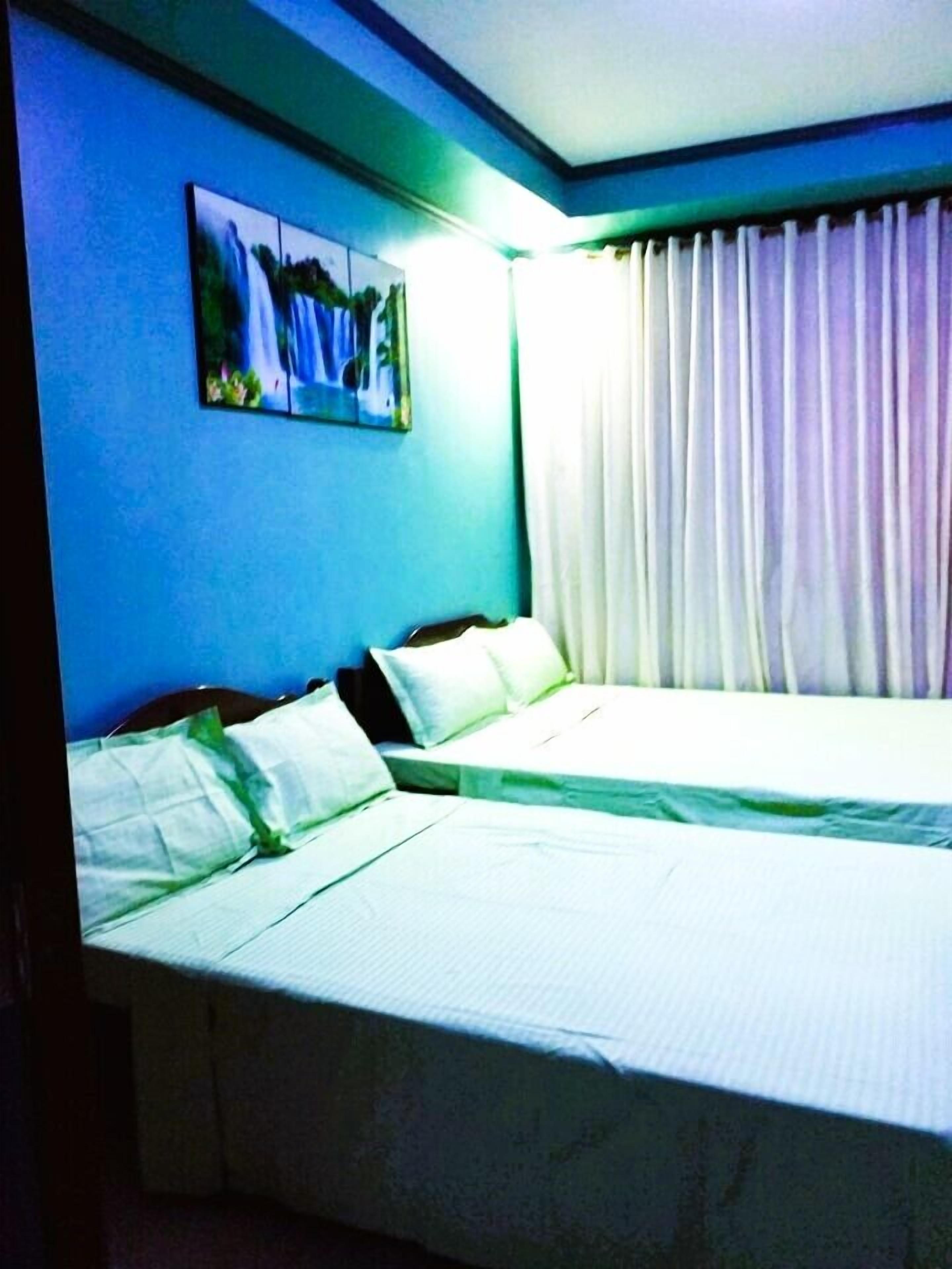 Una habitación de hotel con dos camas, un cuadro en la pared y una ventana con cortinas.