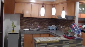 Una cocina con armarios de madera, salpicadero de azulejos e iluminación colgante.