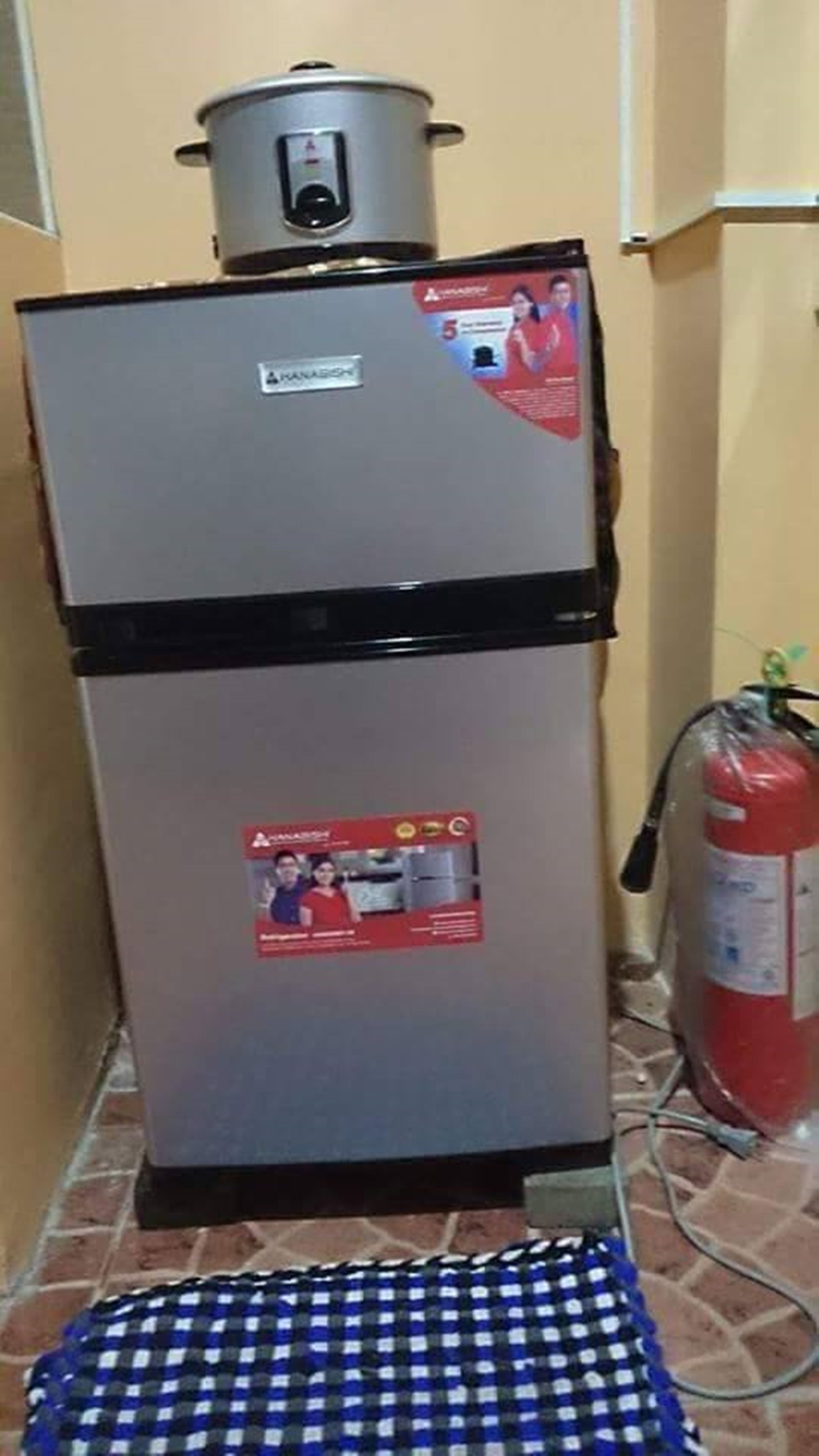 A compact kitchen with a refrigerator, a stove, and a fire extinguisher.